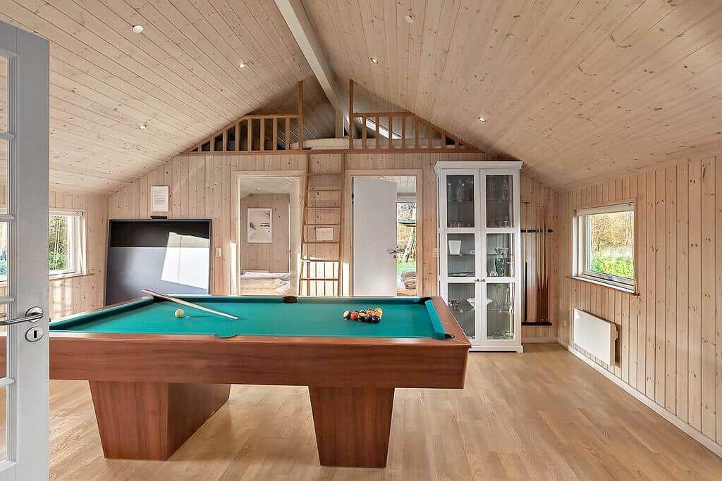 Room with pool table, wood walls, and loft area.