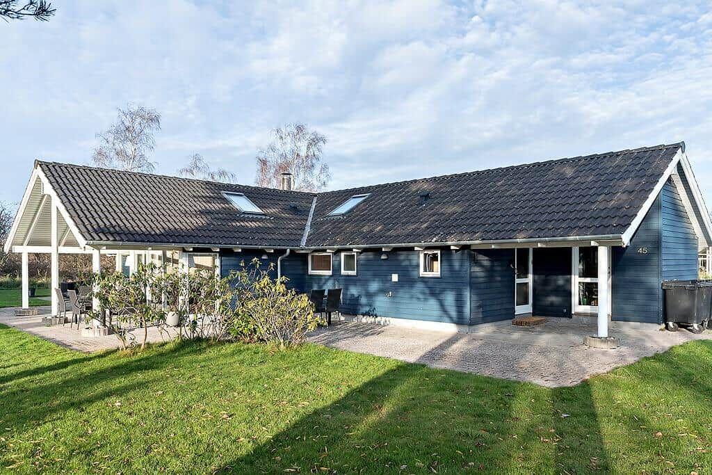 A blue holiday home with terrace and garden. Two roof windows are visible.