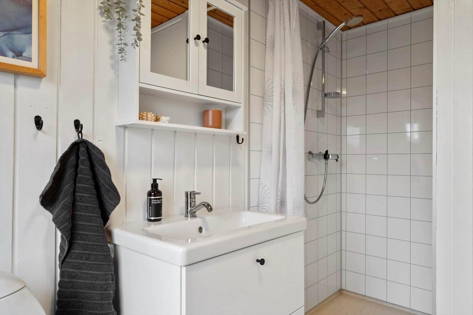 Badezimmer mit Dusche, Waschbecken und Spiegelschrank.