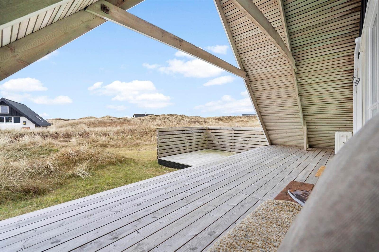 Holzterrasse mit Sitzbank und Blick auf Dünenlandschaft