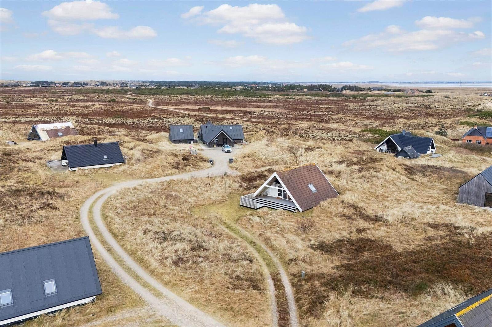 Aerial view of several cabins on a grassy landscape with winding dirt paths.