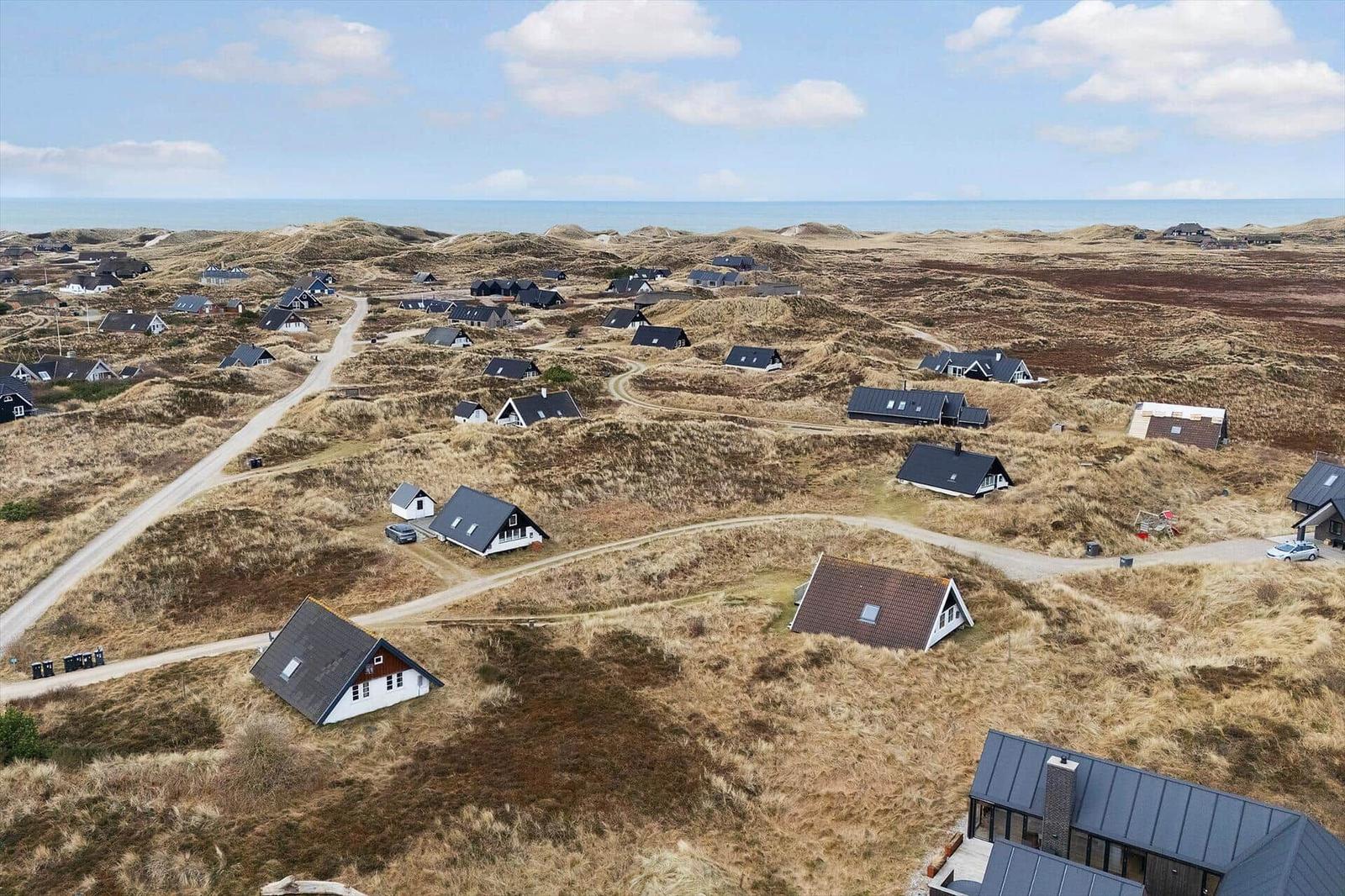 Dorf auf Dünen mit Häusern und Blick auf das Meer.