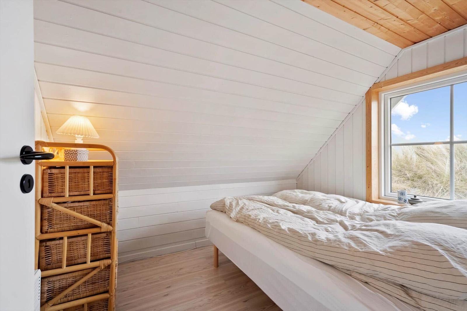 Schlafzimmer mit Bett, Fenster und Holzwand