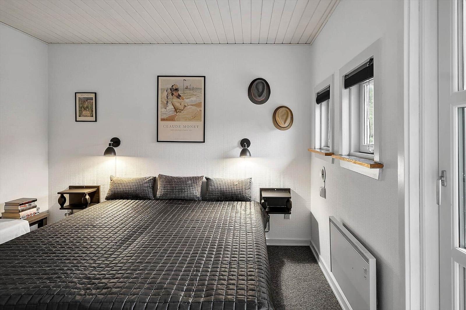 Bedroom with bed, wall art, and windows.