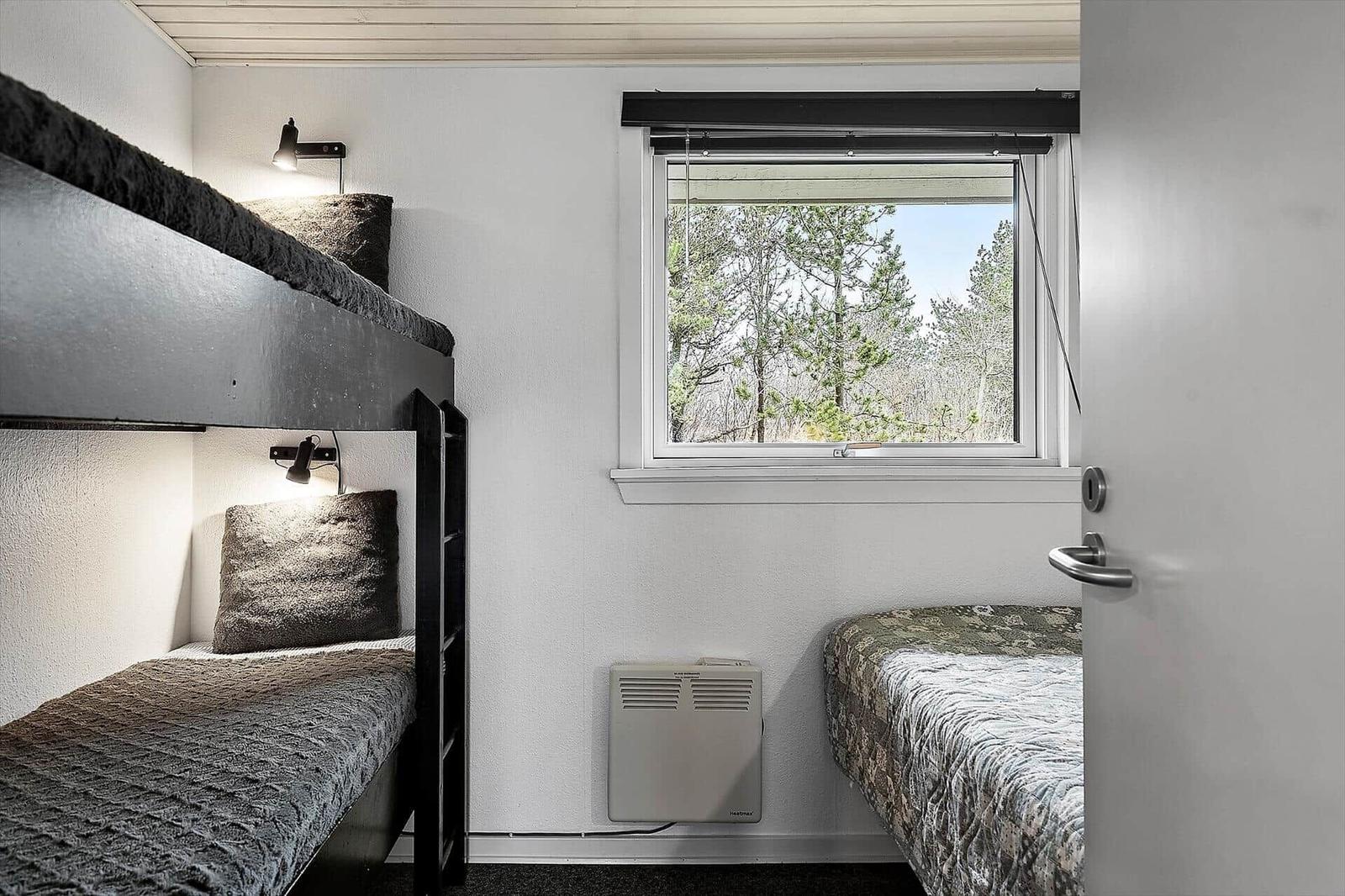 Room with bunk bed, single bed, and window view of trees.