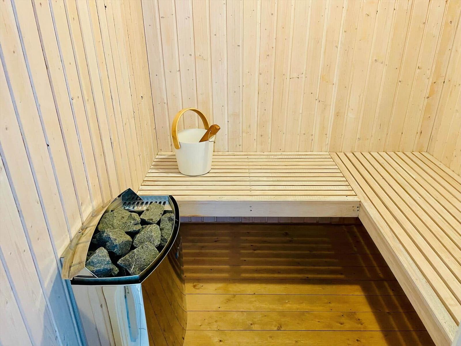 Sauna with wooden bench, stone heater, and bucket with ladle.