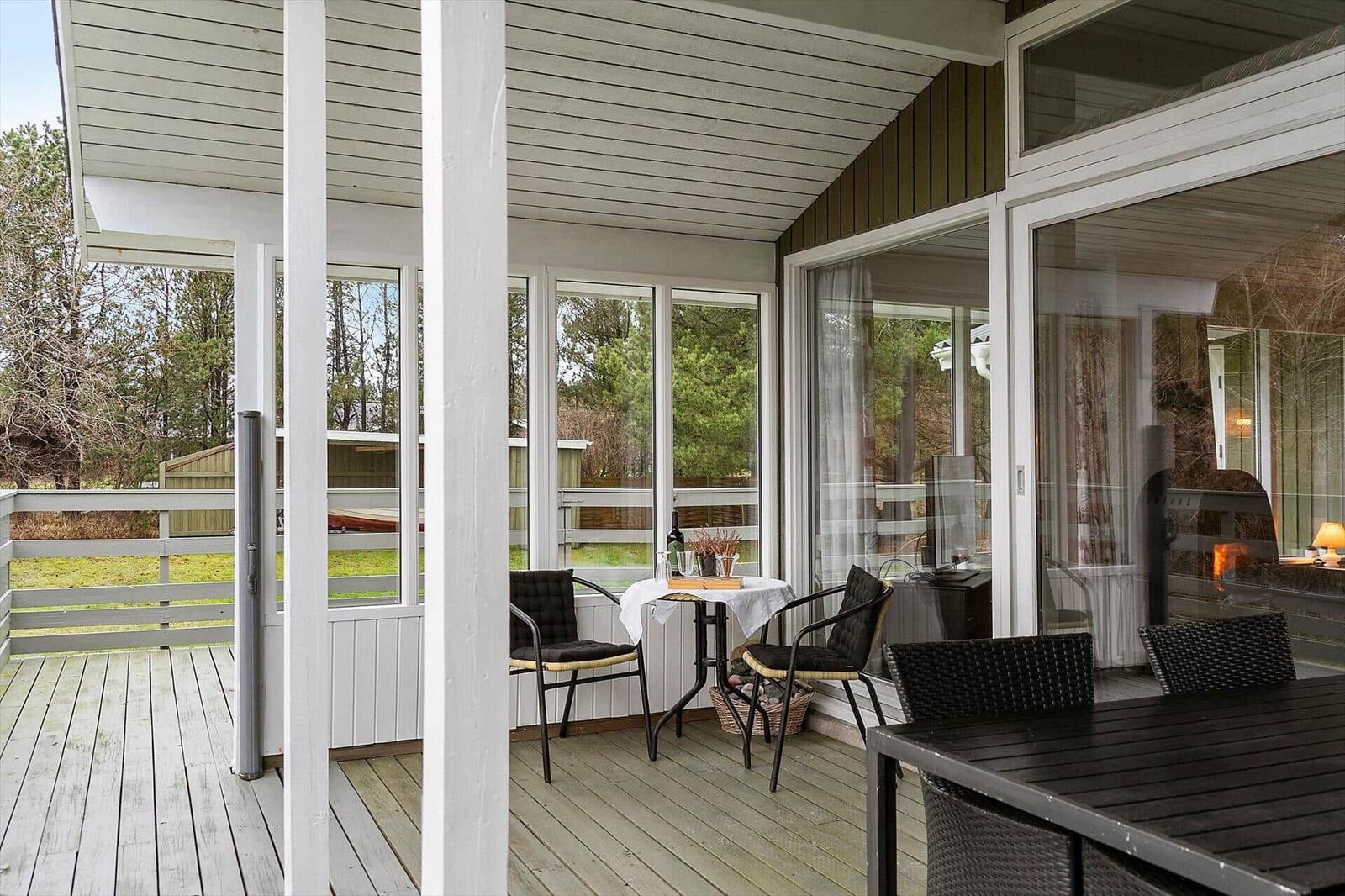 Deck with table, chairs, and view of green areas.