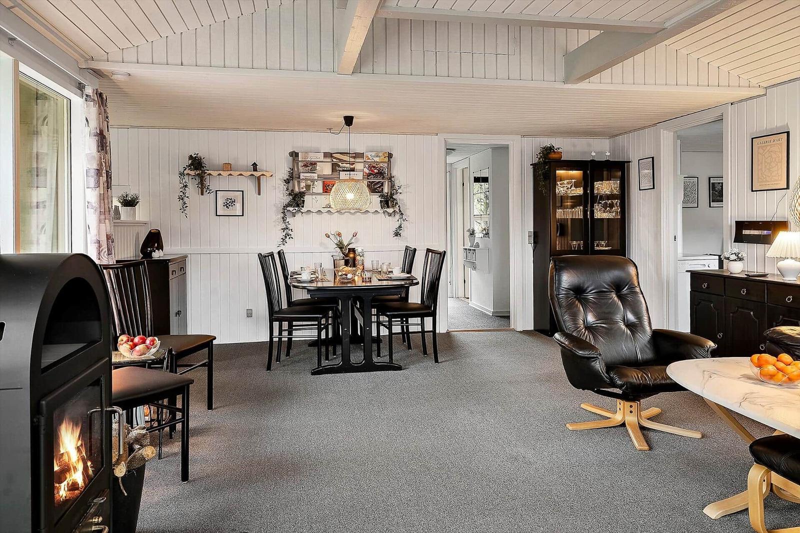 Living and dining area with fireplace, dining table, and leather armchair.