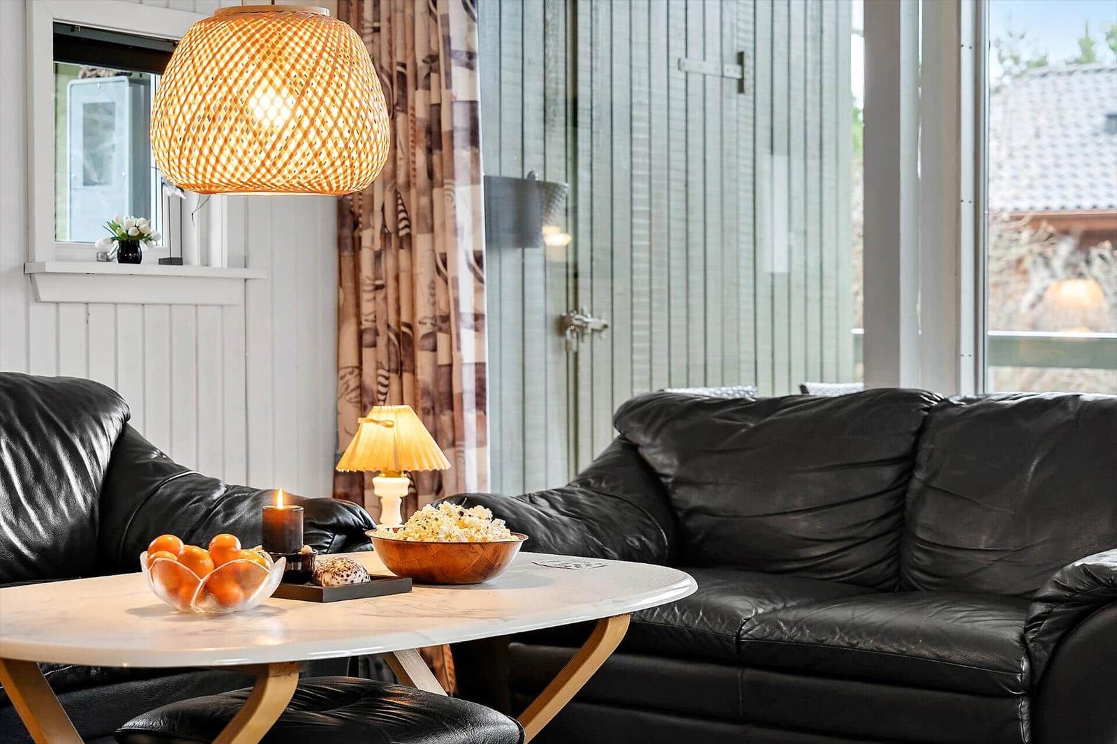 Black leather sofas around a round table with fruit and popcorn.