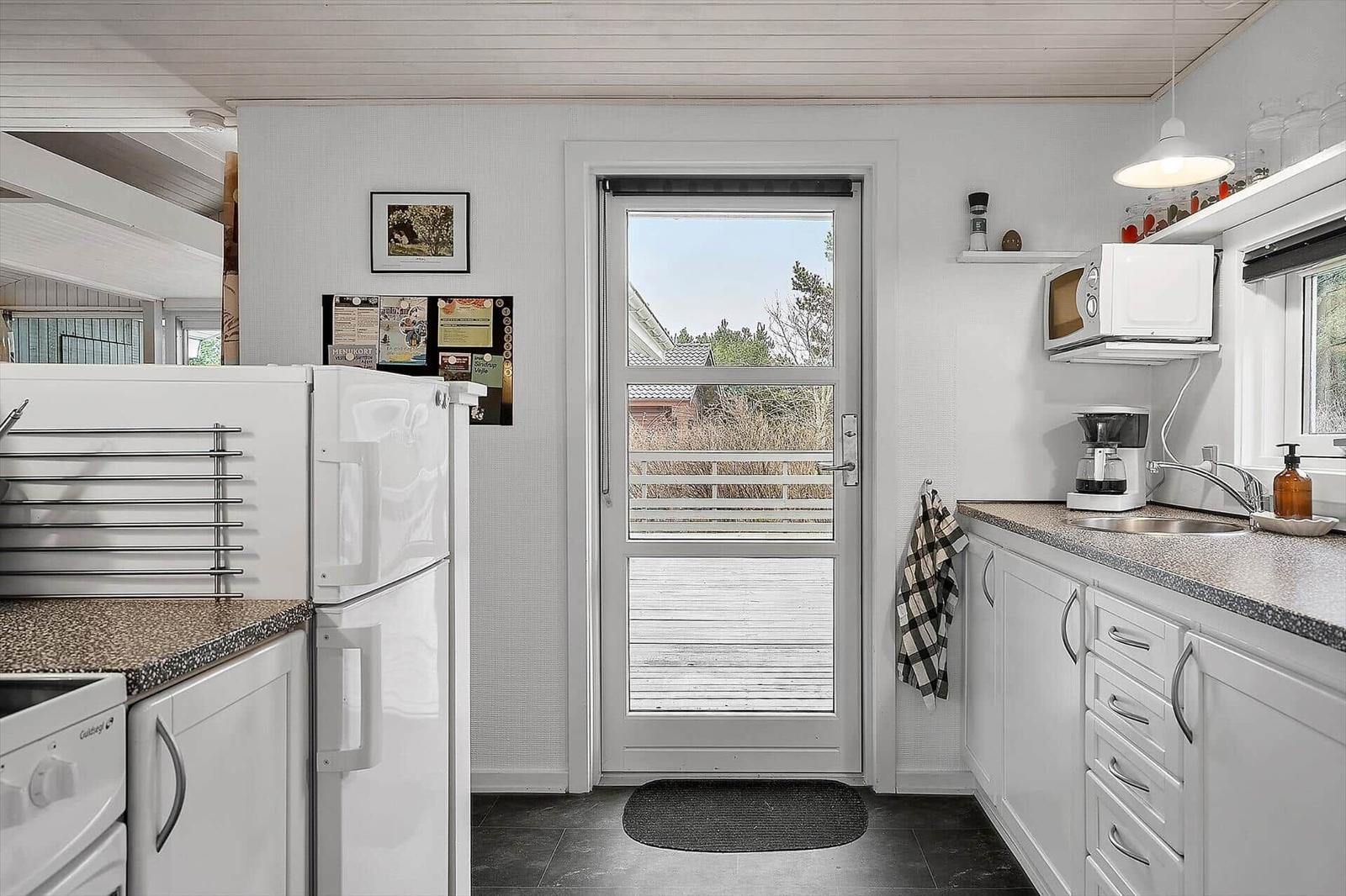 Kitchen with white cabinetry, refrigerator, and door to balcony.