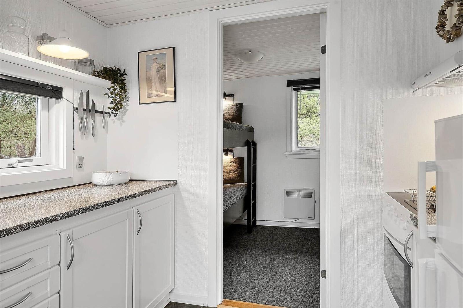 Kitchen with countertop and view into bedroom with bunk bed.