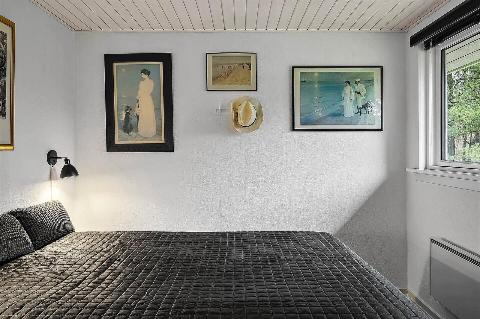 Bedroom with bed, wall art, and window.