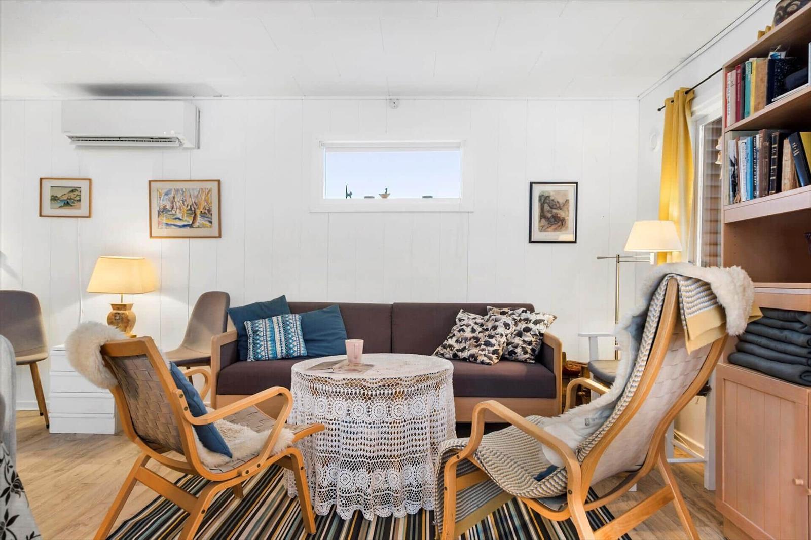 Wohnzimmer mit Sofa, zwei Stühlen, Tisch und Bücherregal.