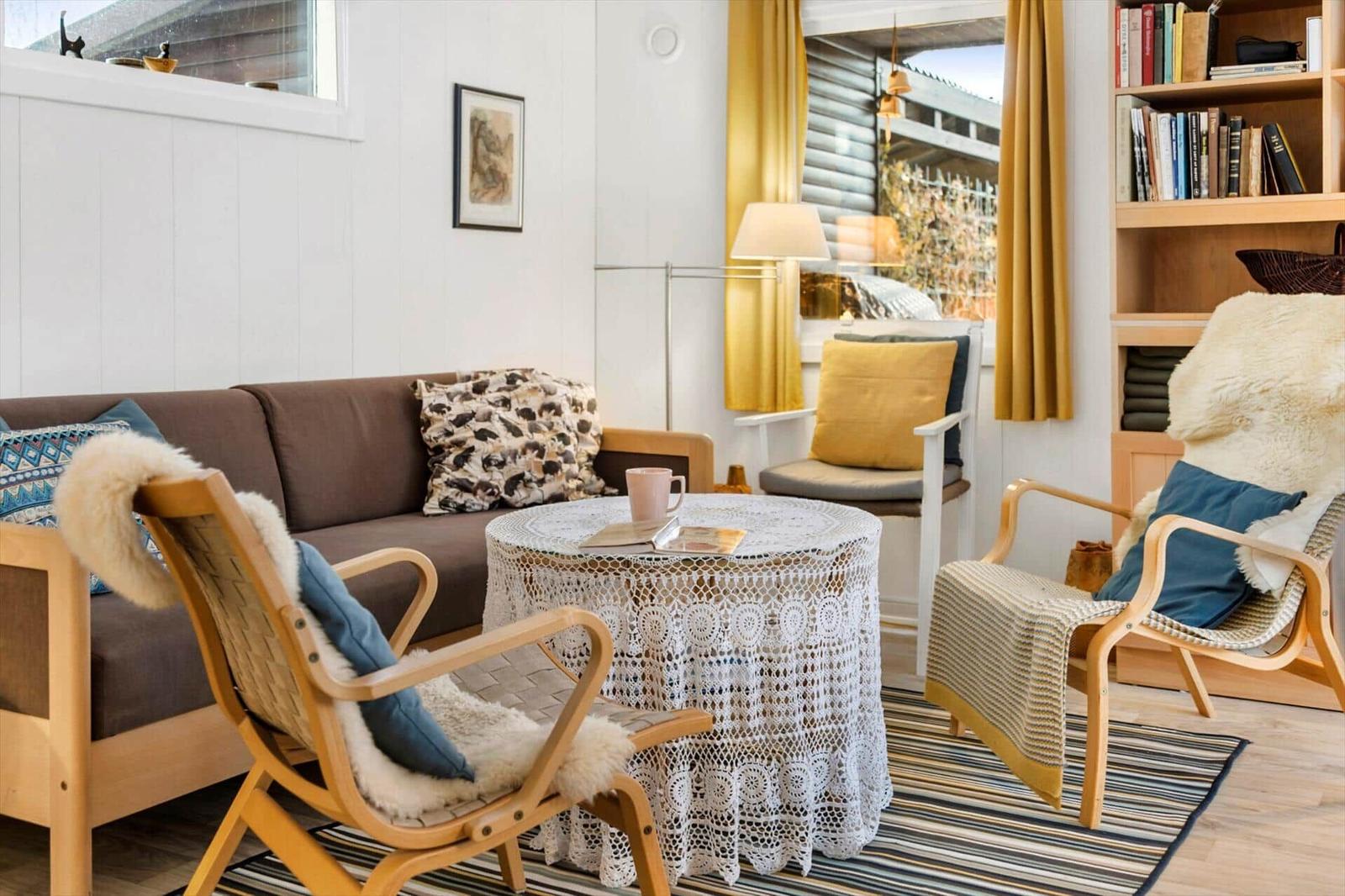 Wohnzimmer mit Sofa, Stühlen und runden Tisch mit Häkeldecke.