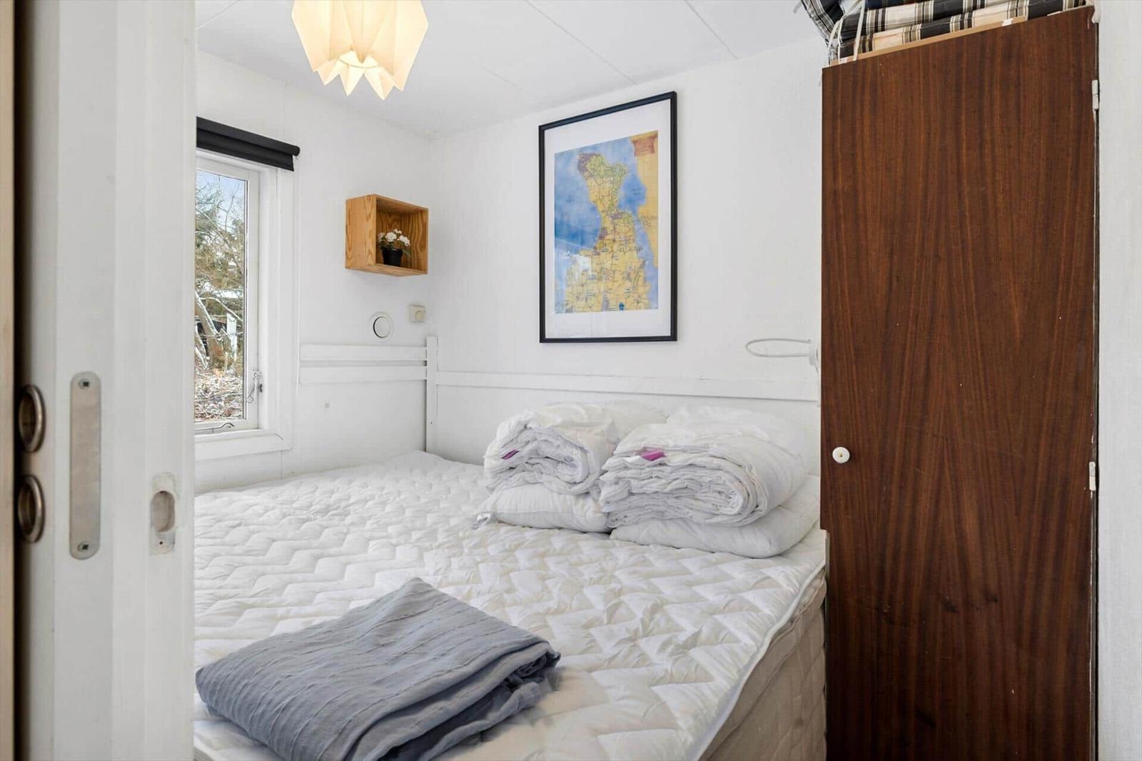 Schlafzimmer mit Bett, Fenster und Wandbild.