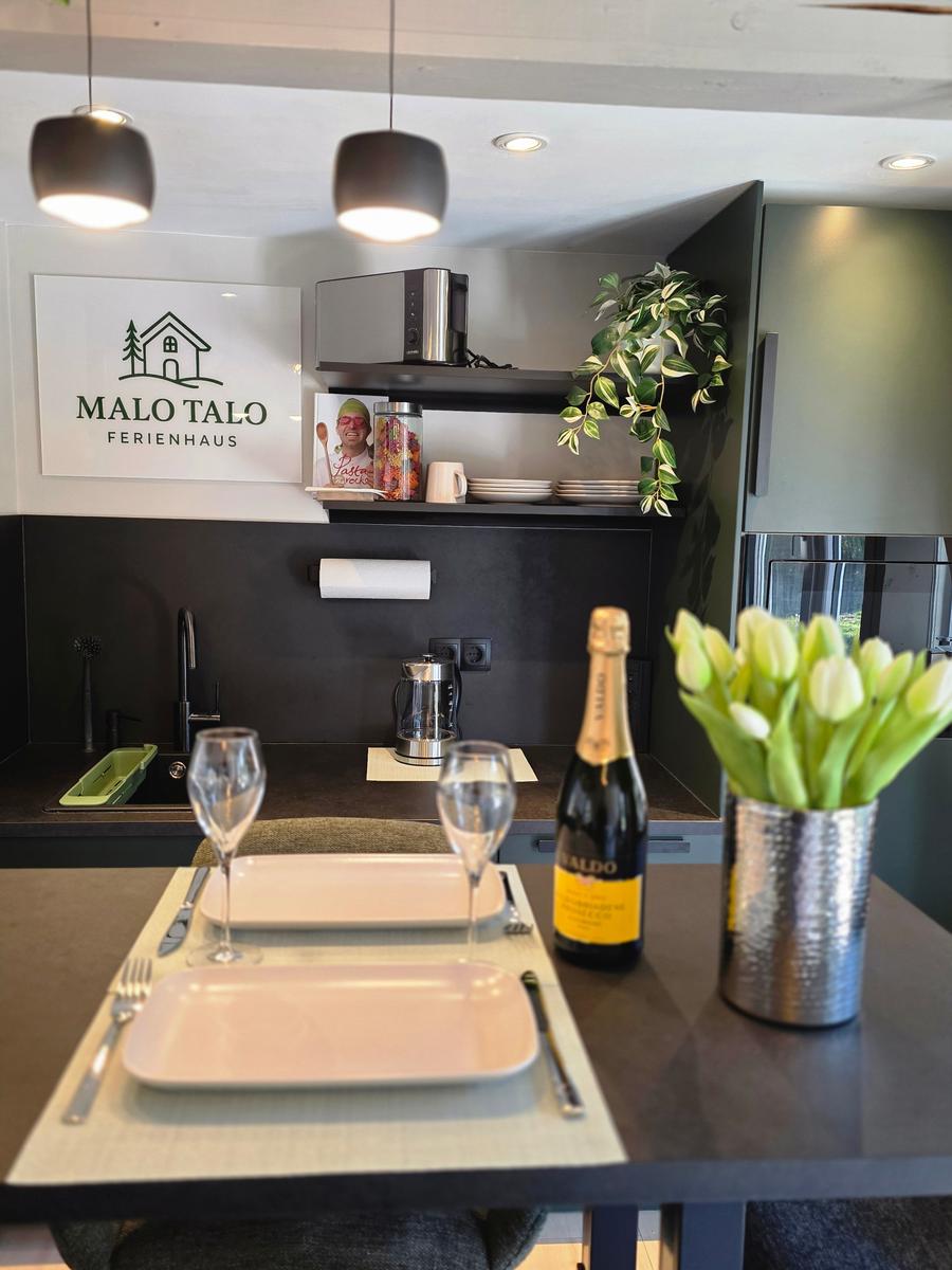 Küche mit Tisch, Flasche Champagner und Blumen