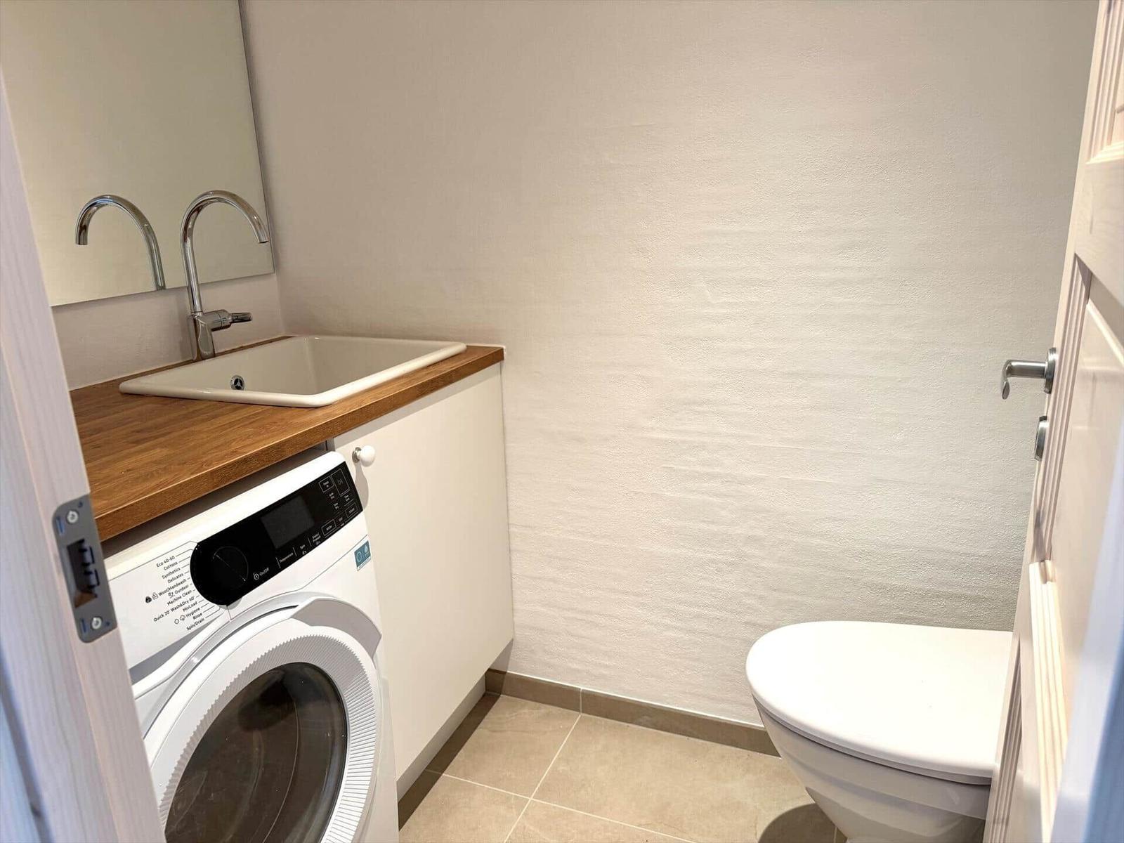 Badezimmer mit Waschmaschine, Waschbecken und Toilette