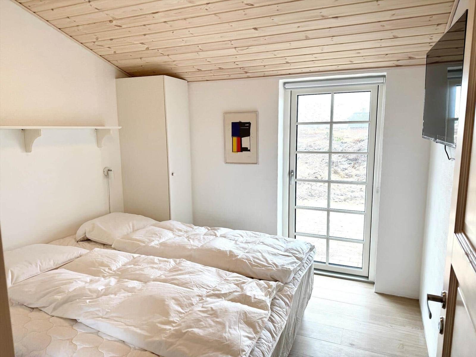 Schlafzimmer mit Doppelbett, Schrank und Fenster zur Aussicht.