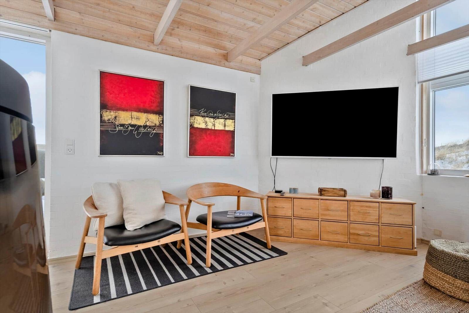 Wohnzimmer mit TV, zwei Sesseln und Holzmöbeln.