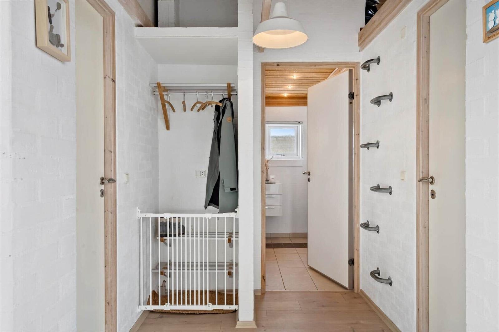 Flur mit Garderobe, Tür und Bad. Wand mit Handgriffen.