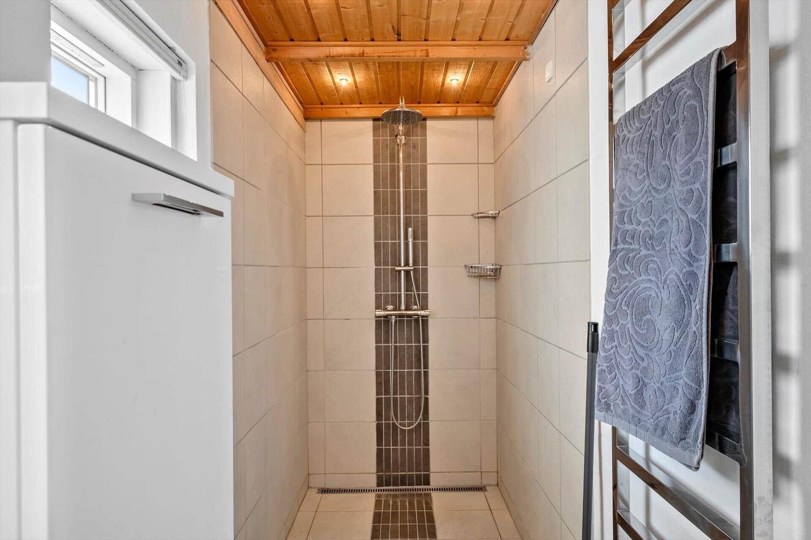 Dusche mit Holzdecke, Fliesenwand und Handtuchhalter