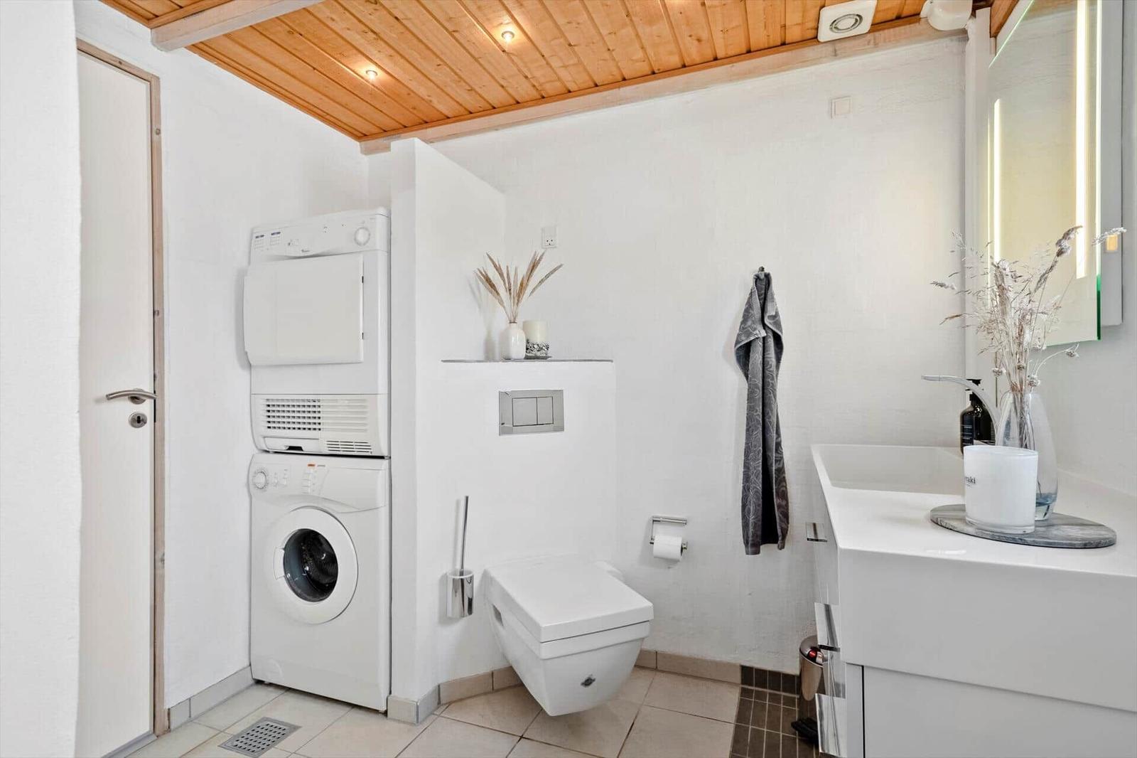 Badezimmer mit Waschmaschine, Trockner, WC und Waschtisch.