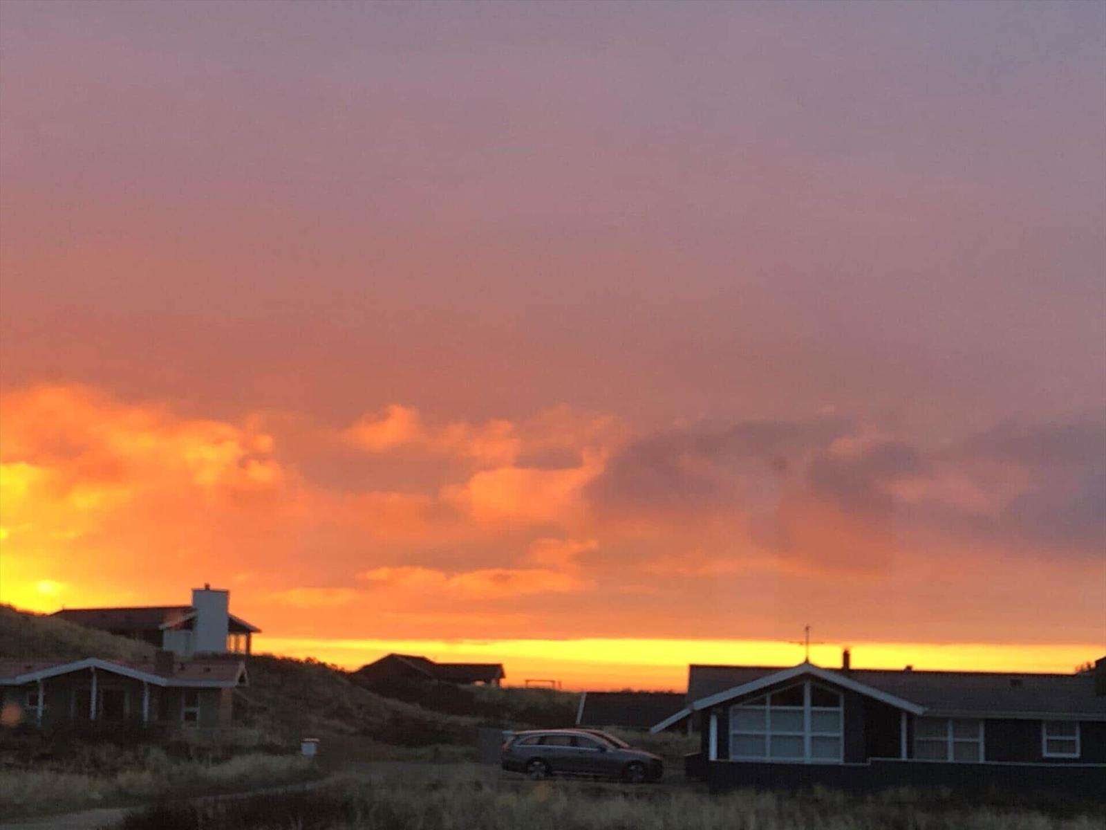 Sonnenuntergang über Häusern und Grasland