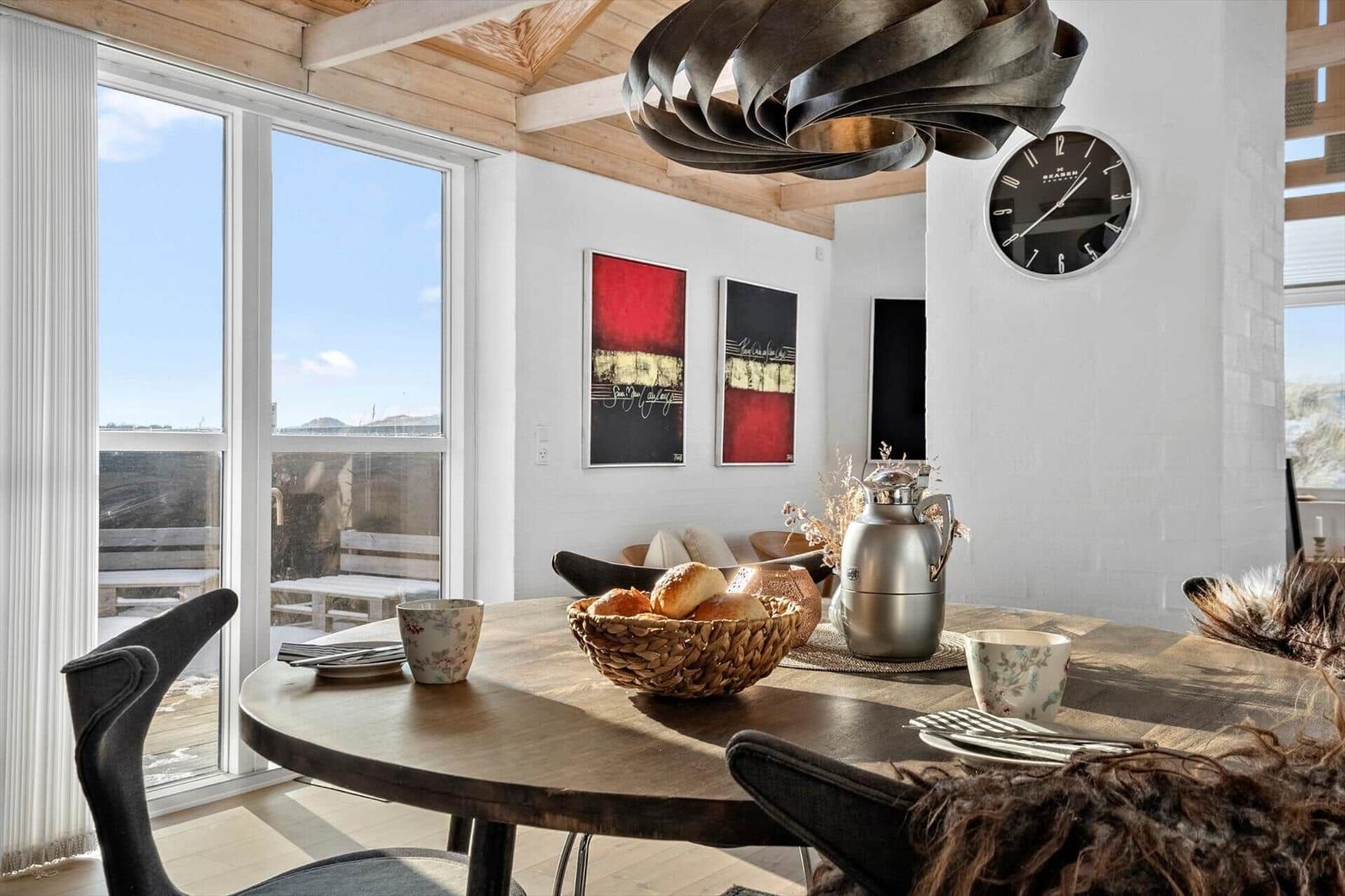 Runder Tisch mit Stühlen, Wanduhr und Fenster zum Balkon