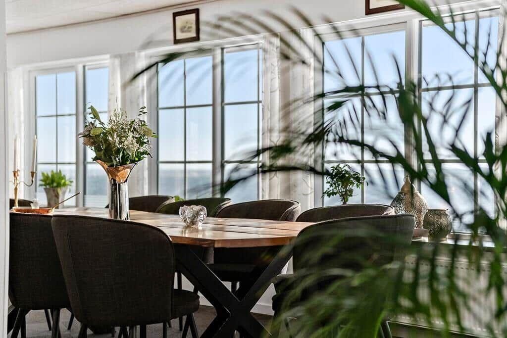 Dining room with wooden table, chairs, and water view.