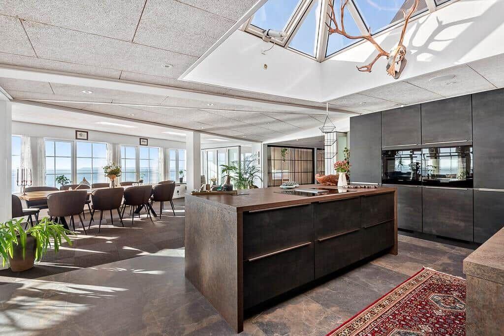 Modern kitchen with island, dining area, and sea view.