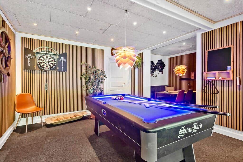 Room with pool table, dartboard, and seating areas.