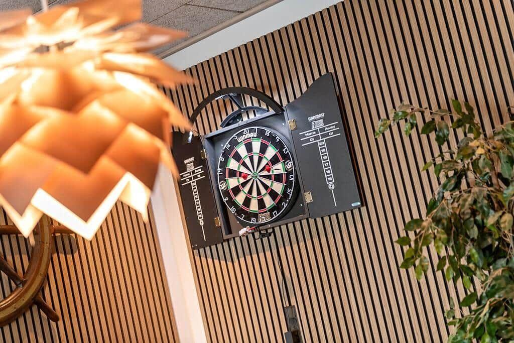 Wall-mounted dartboard with plant and lamp lighting