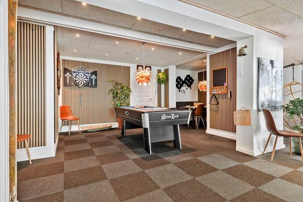 Room with pool table, dartboard, and seating areas.