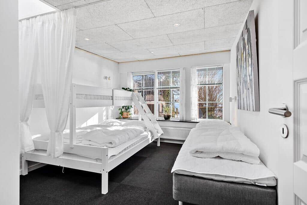 Room with double bed, bunk bed, and windows