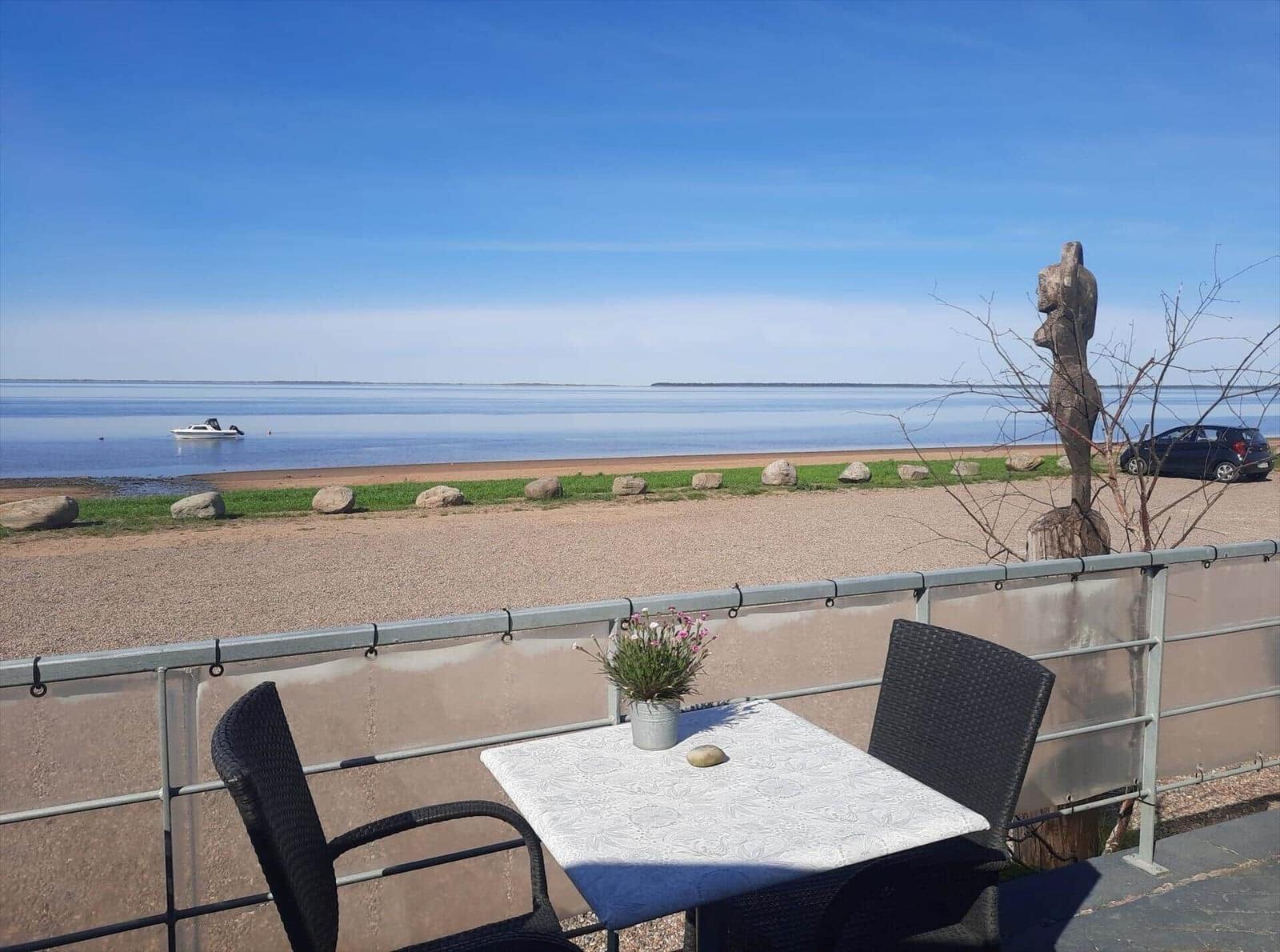 Terrace with table and chairs offers view of sea and beach.