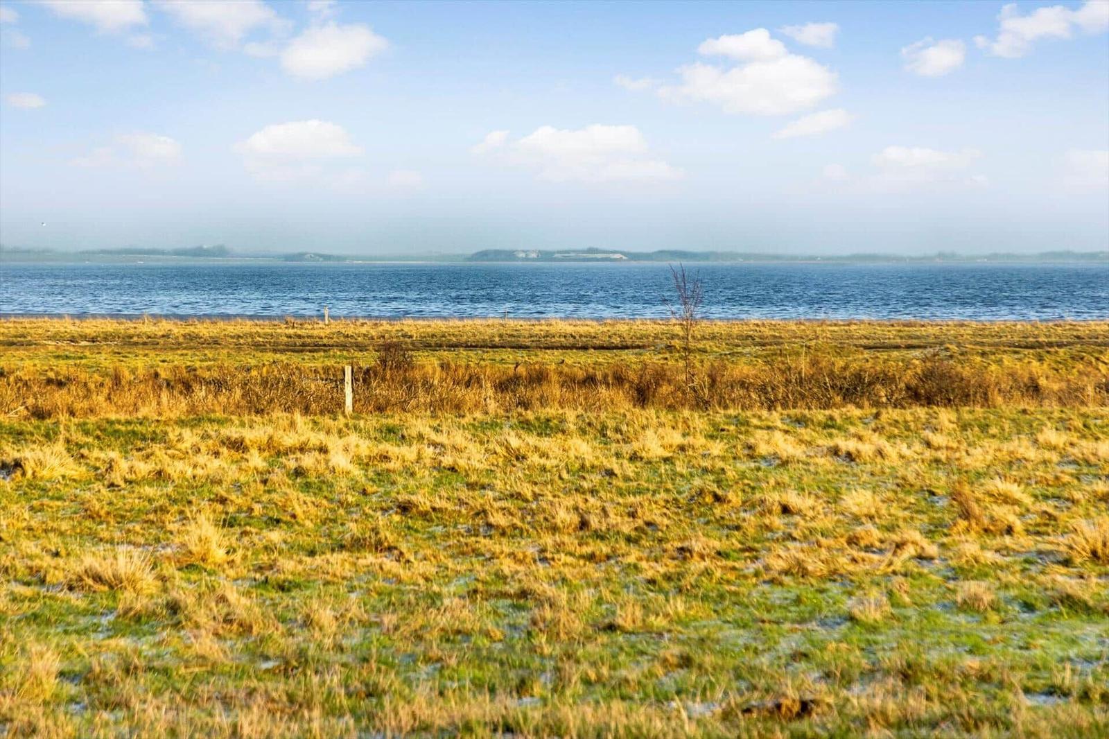 Weiteres Uferland mit Blick auf das Wasser und fernen Horizont.