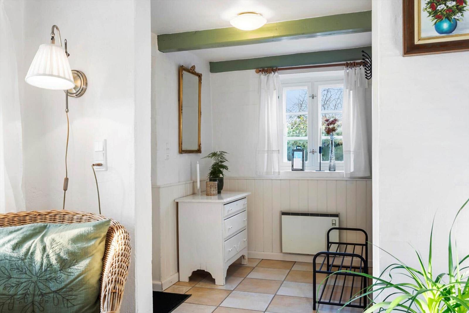 Ein Raum mit weißem Schrank, Fenster und grünen Balken.