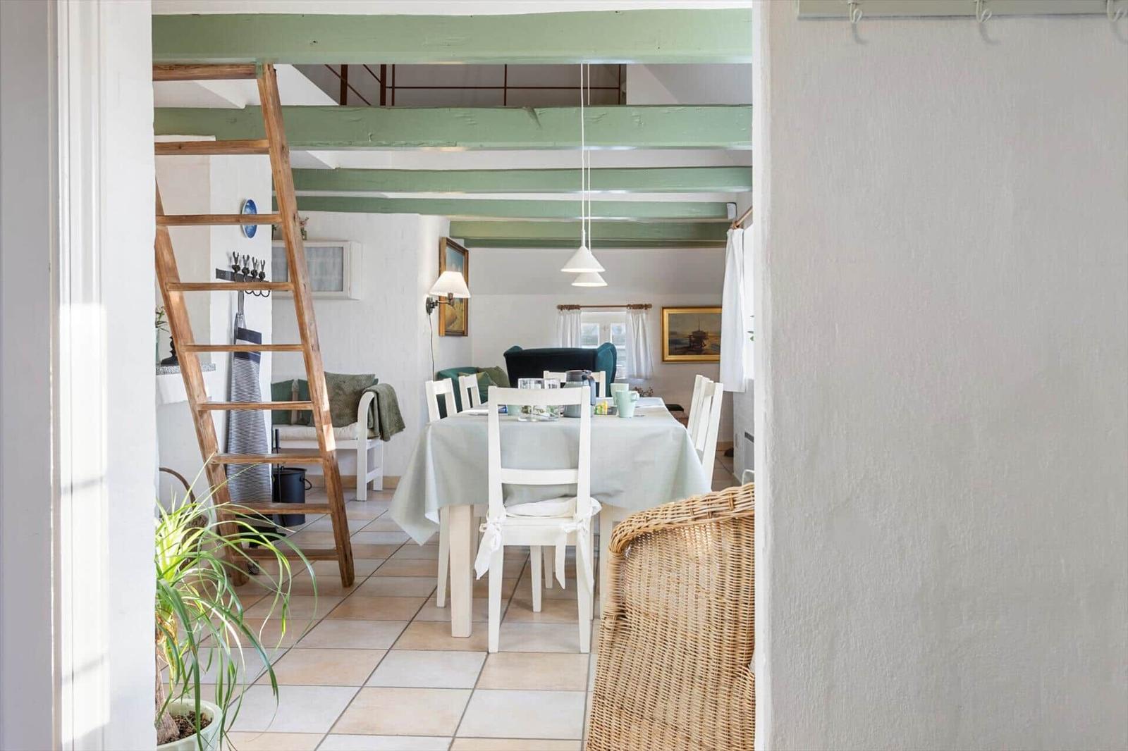 Esszimmer mit Tisch, Stühlen und grünen Balken.