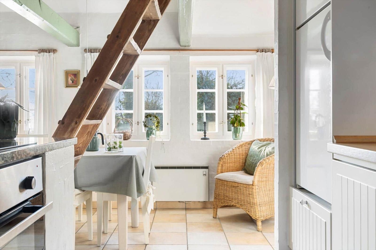 Küche mit Essbereich und Holztreppe zur oberen Etage.