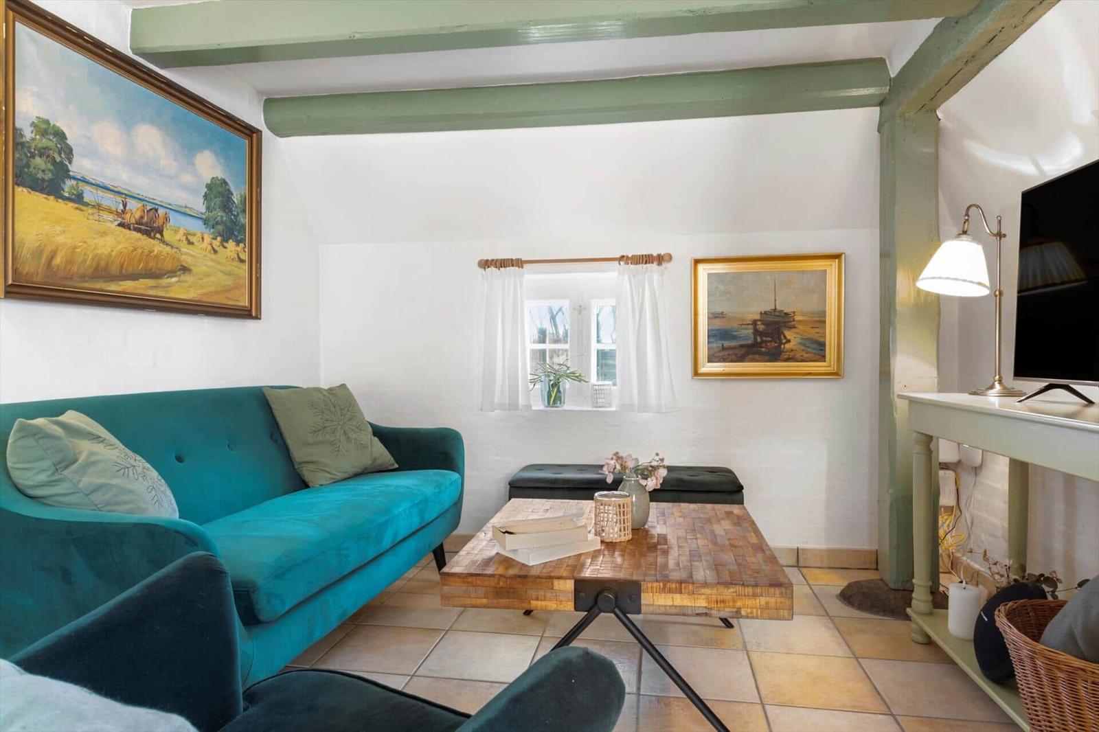 Ein Wohnzimmer mit grünem Sofa, Holztisch und Wandbildern.