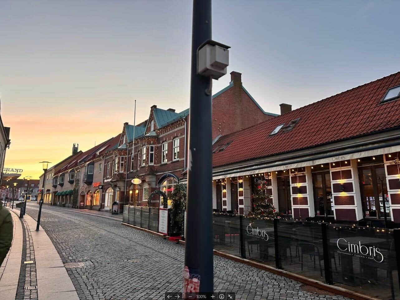 Straßenszene mit historischen Gebäuden und einem Restaurant im Abendlicht.
