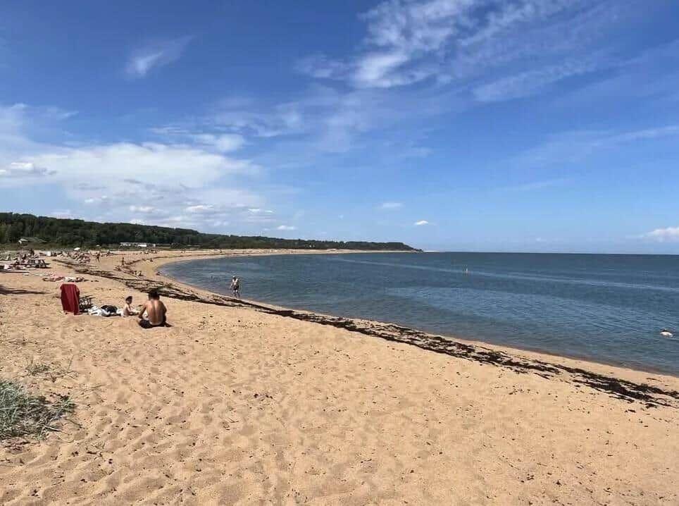 Strand mit Sand, Meer und einigen Menschen in der Ferne.