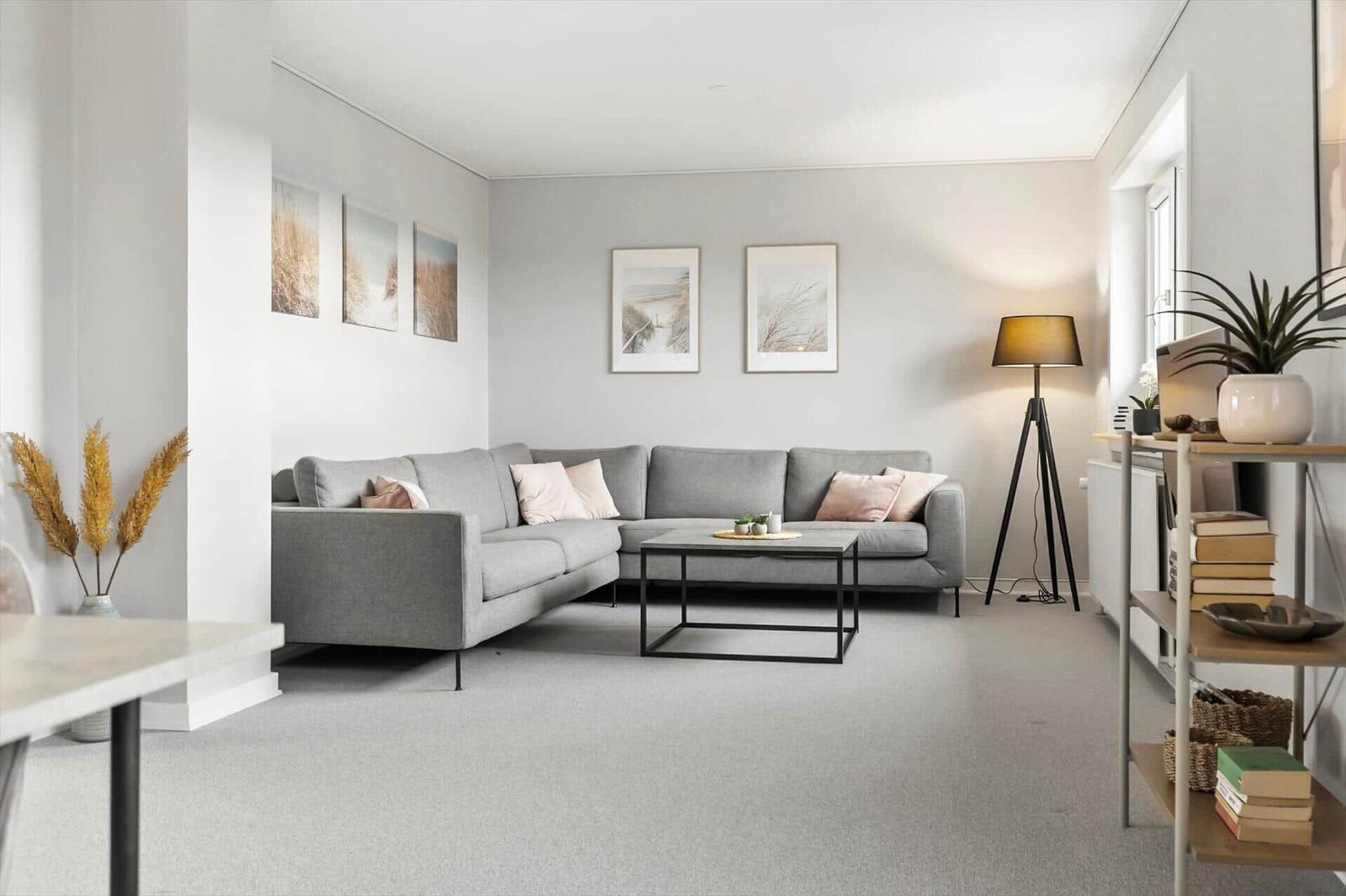 Ein Wohnzimmer mit grauem Sofa, Tisch und Wandbildern.