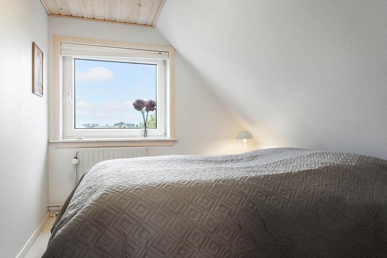 Schlafzimmer mit Bett, Fenster und Lampe.