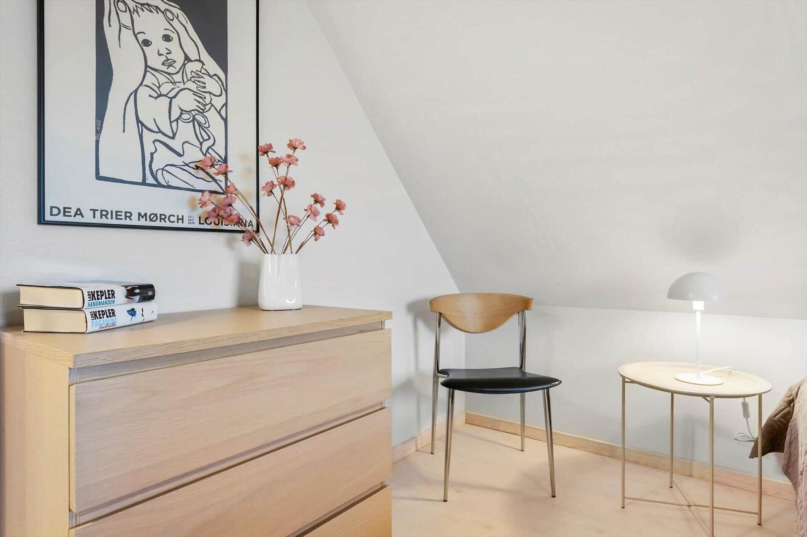 Schlafzimmer mit Schrank, Stuhl und Nachttisch unter schräger Decke.