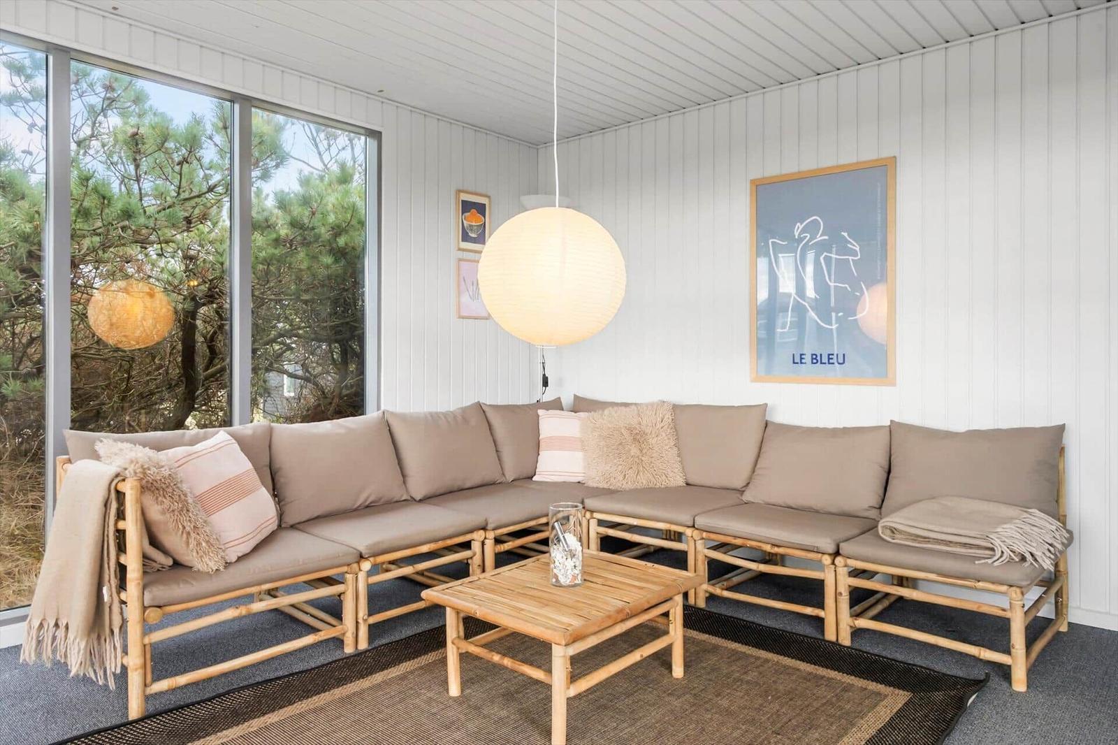 Wohnbereich mit Sofa, Tisch und großen Fenstern.