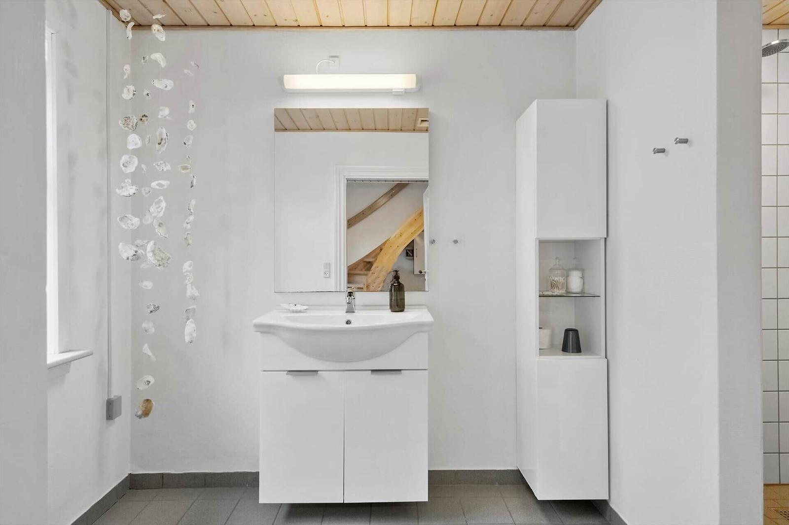 Badezimmer mit Waschbecken, Spiegel und Schrank. Wanddekoration aus Muscheln.