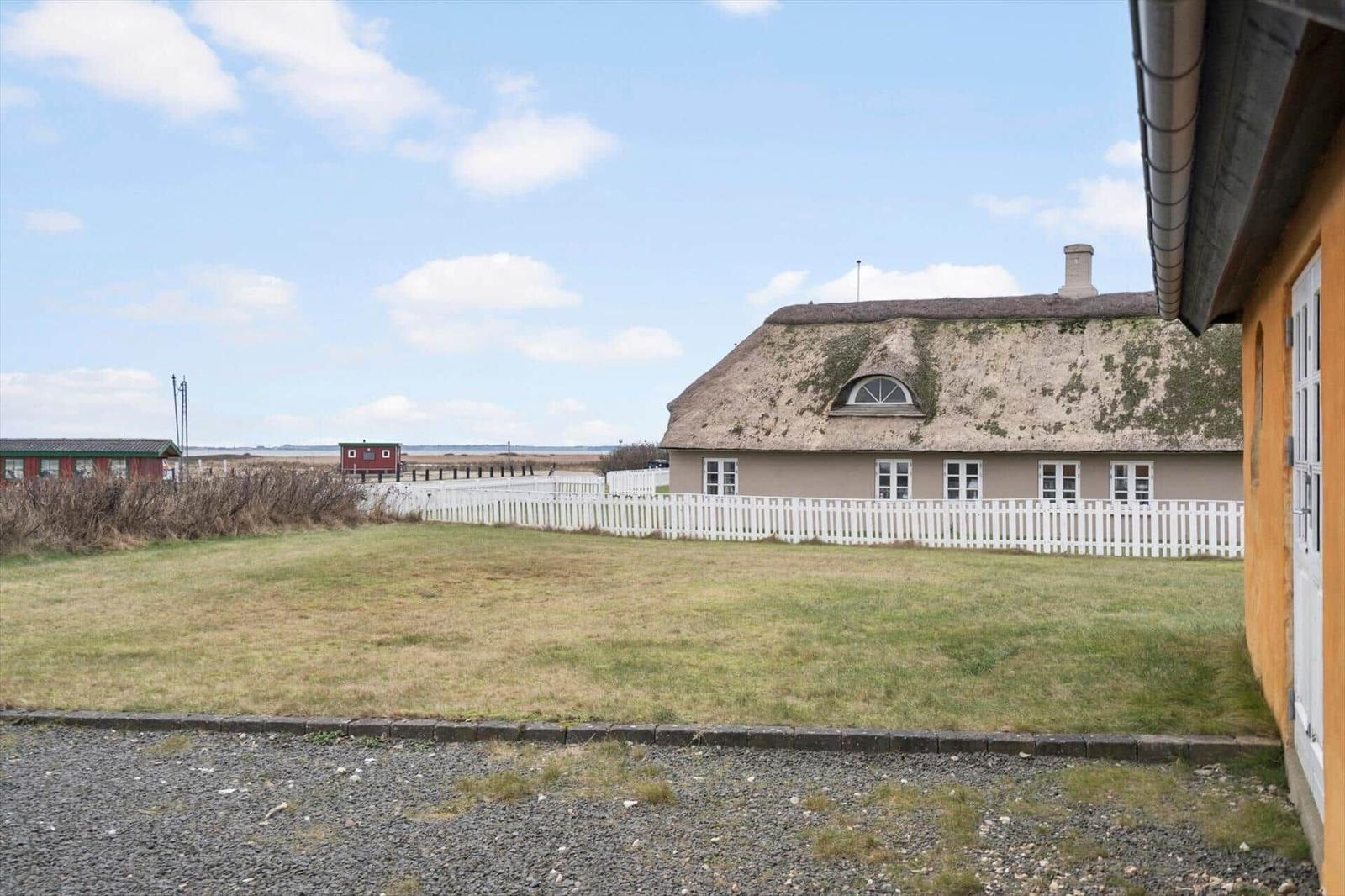 Haus mit Strohdach und weißem Zaun im Freien.