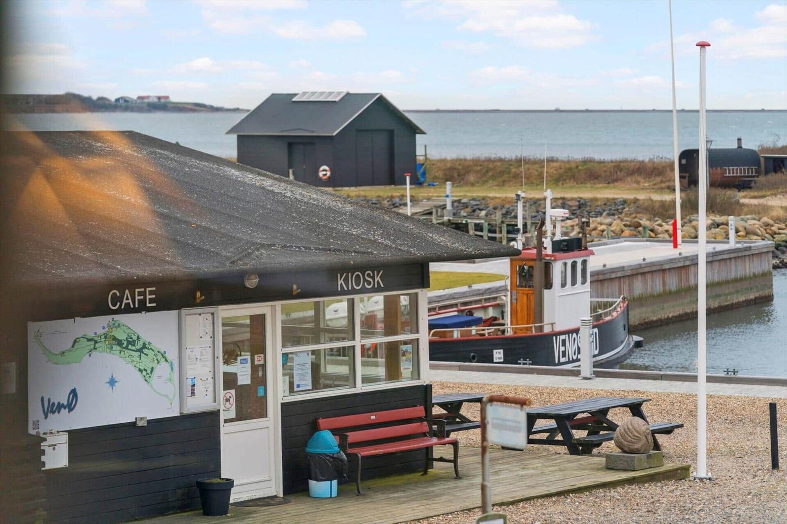 Café-Kiosk am Hafen mit Bootsanlegestelle und Blick aufs Wasser.