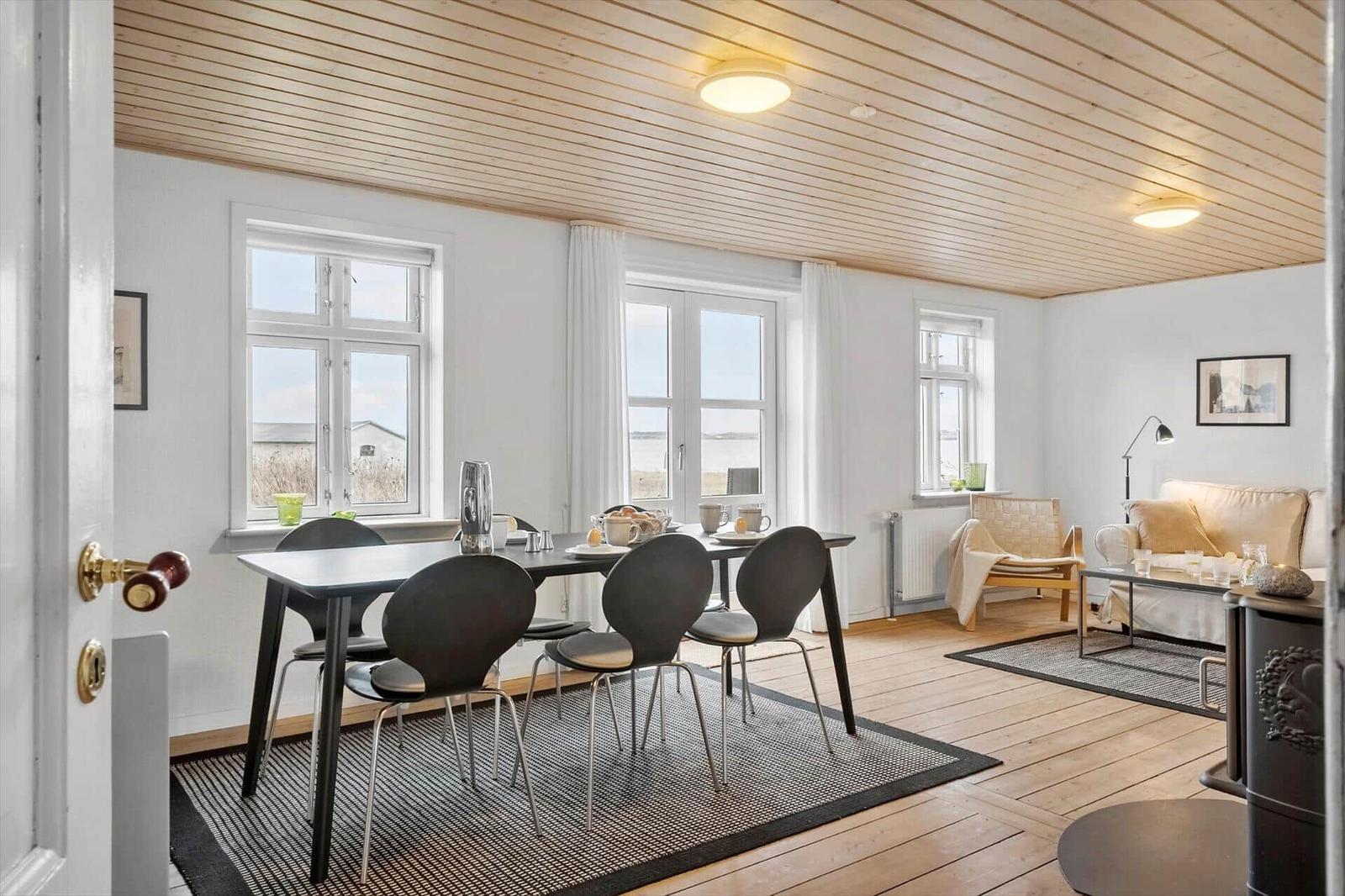 Esszimmer mit Tisch und Stühlen, Wohnbereich mit Sofa und Fenstern